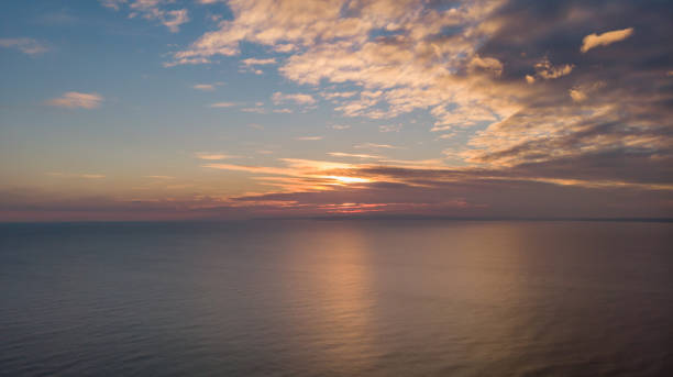 An aerial view of a sunset with reflection on the sea and white clouds An aerial view of a sunset with reflection on the sea and white clouds boscombe photos stock pictures, royalty-free photos & images