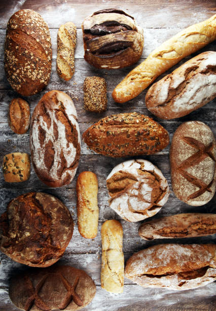 istock Different kinds of bread and bread rolls on board from above. Kitchen or bakery 1138235754