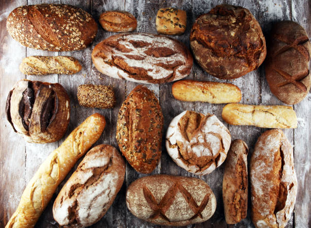 istock Different kinds of bread and bread rolls on board from above. Kitchen or bakery 1138236401