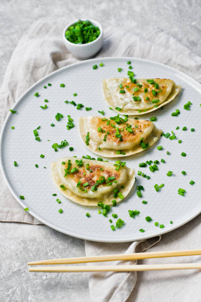 istock Chinese dumplings, chopsticks, fresh green onions. Gray background, top view, 1138238600