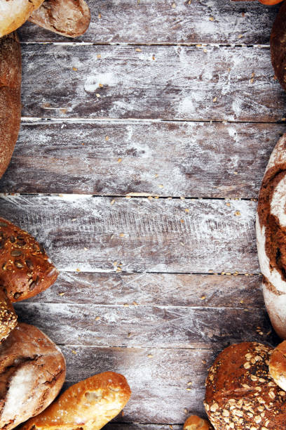 Different kinds of bread and bread rolls on board from above. Kitchen or bakery