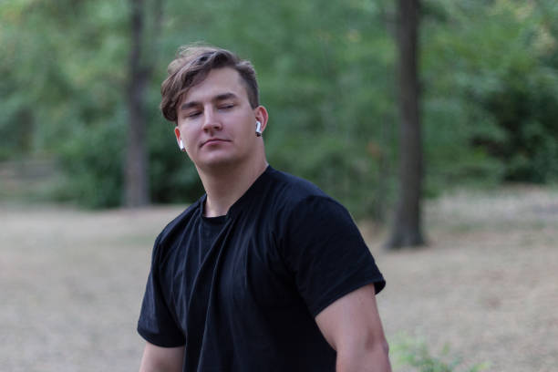 istock Young handsome caucasian man with arrogant expression looking down, self-confident and assuming. Dark curly hair, white earphones, earring, black casual shirt. 1138243066