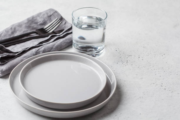 Empty plate and glass of water, white background. Medical fasting concept. stock photo