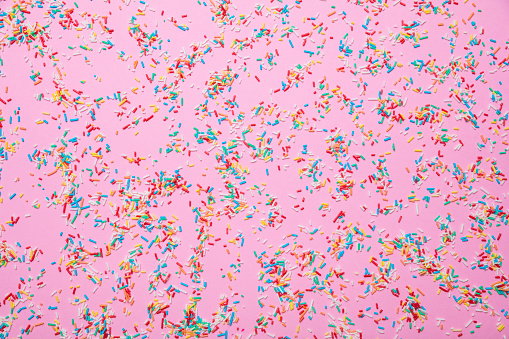 Birthday concept. Colorful sprinkles on pastel pink background, top view