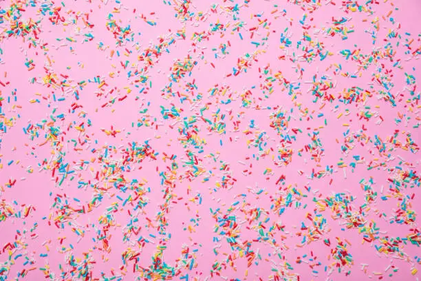 Photo of Birthday concept. Colorful sprinkles on pink background