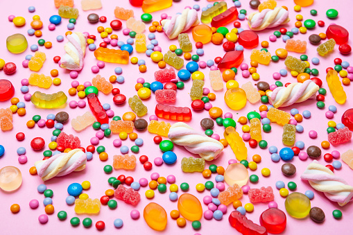 Birthday concept. Colorful assorted sweet candies on pastel pink background, closeup view