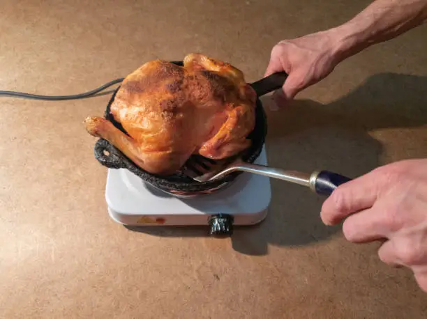 man turns a fried chicken in a pan on a hotplate.Cooking Fried Chicken