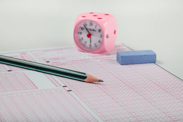 istock high school or university student hands taking exams, writing examination on paper answer sheet optical form of standardized test on desk doing final exam in classroom. Education literacy concept. 1138247262