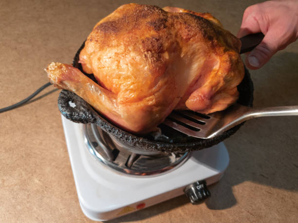 The man turns a fried chicken in a pan on a hotplate.Cooking Fried Chicken