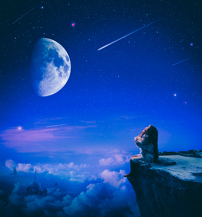 Cute little girl sitting on the cliff up high in the night of falling stars making a wish