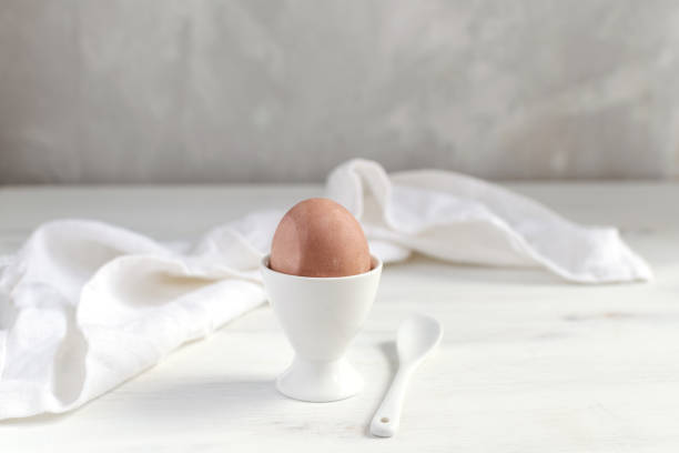 istock Naturally dyed easter egg for breakfast, dyed eggs in white basket, white egg cup, white wooden table - minimal easter concept 1138249985