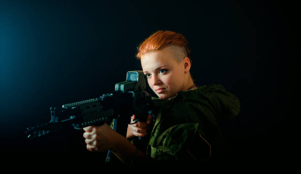 Young woman with red hair, hold machinegun in military uniform. horizontal background Young woman with red hair in military green uniform basement russian escort stock pictures, royalty-free photos & images