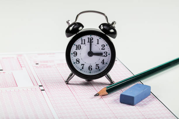 istock high school or university student hands taking exams, writing examination on paper answer sheet optical form of standardized test on desk doing final exam in classroom. Education literacy concept. 1138252770