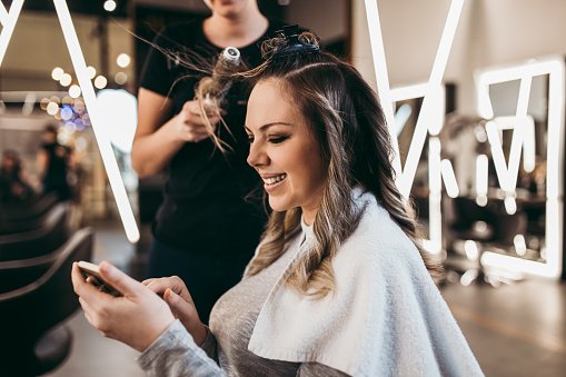 Beautiful brunette woman with long hair at the beauty salon getting a hair blowing. Hair salon styling concept.