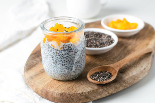 chia pudding in glas mit mandelmilch und mango auf weißem hintergrund - padding stock-fotos und bilder