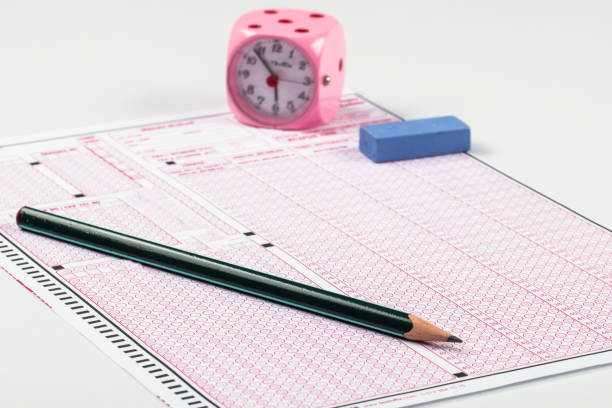 istock high school or university student hands taking exams, writing examination on paper answer sheet optical form of standardized test on desk doing final exam in classroom. Education literacy concept. 1138253683