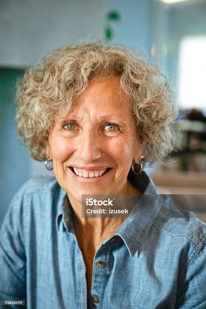 Portrait of happy senior woman at nursing home Portrait of smiling elderly female. Senior woman is sitting at nursing home. She is in blue casuals. Women Stock Photo