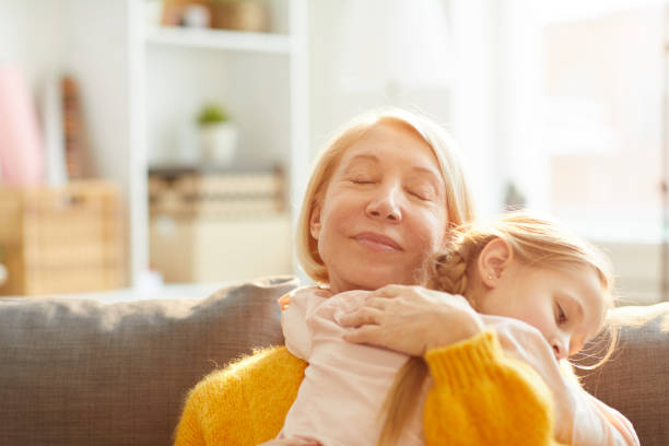 Portrait of smiling mature woman with eyes closed embracing cute little girl tenderly, copy space