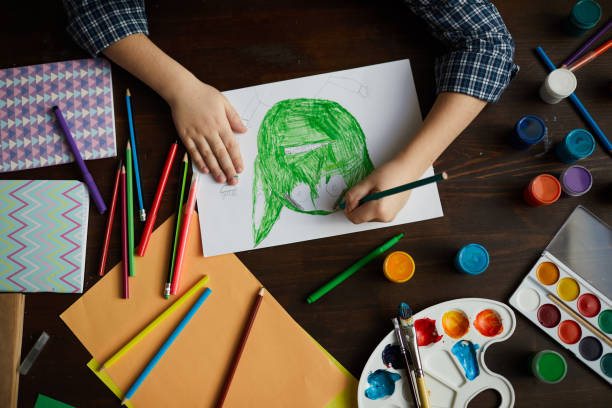 Little Boy Drawing Monster Above view closeup of unrecognizable little boy drawing picture of green monster in art class, copy space crayon drawing photos stock pictures, royalty-free photos & images