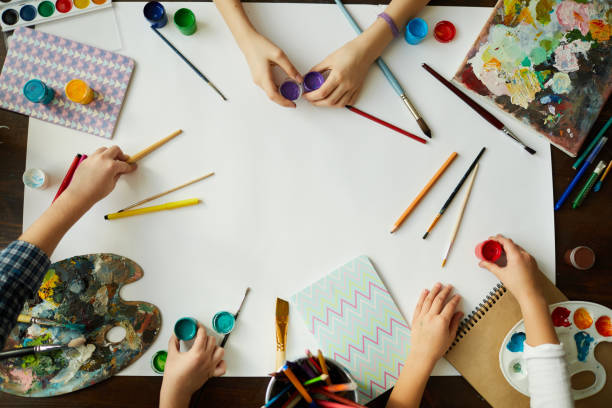 Creative Kids Background Top view of childrens hands over background with art supplies, paints and brushes over white paper, copy space crayon drawing photos stock pictures, royalty-free photos & images