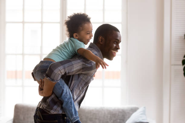 istock Happy little kid riding black dad having fun at home 1138263288