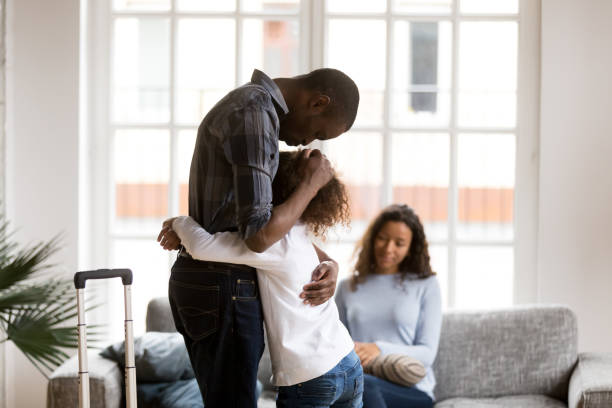 Sad African American girl hug dad leaving home with suitcase Cute sad little African American girl hug dad standing with suitcase leaving for business trip, upset small mixed race kid embrace father saying goodbye, parents separating. Shared custody concept relationship breakup photos stock pictures, royalty-free photos & images