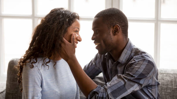istock Happy mixed race couple cuddle on couch looking in eyes 1138263365