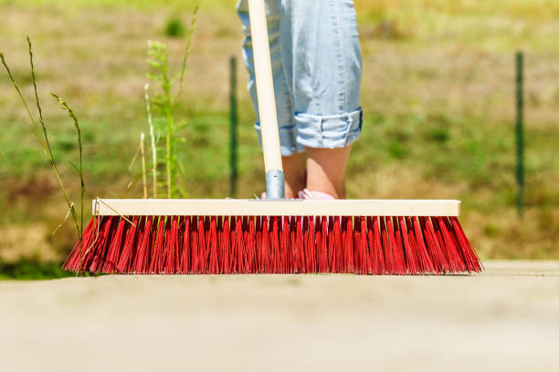 istock Woman using broom to clean up backyard patio 1138267163