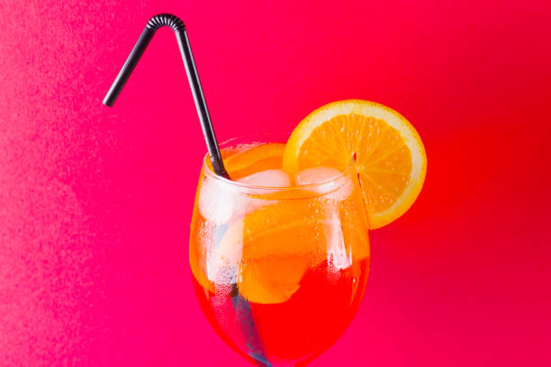 istock Cocktail Spritz on red blue background. Summer alcoholic cocktail with orange slices. Spritz on colored background. Coral colored cocktail in minimalism style 1138268011