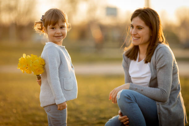 Baby girl giving bouquet of flowers as a present to her mother.