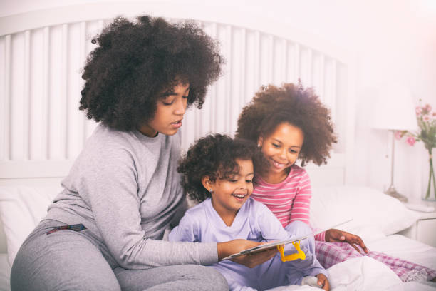 istock Mother with daughters reading books in bed 1138269382