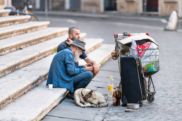 senior viejo vagabundo con perro sentado en el parque de la ciudad en la plaza del carrito - homelessness men white black fotografías e imágenes de stock