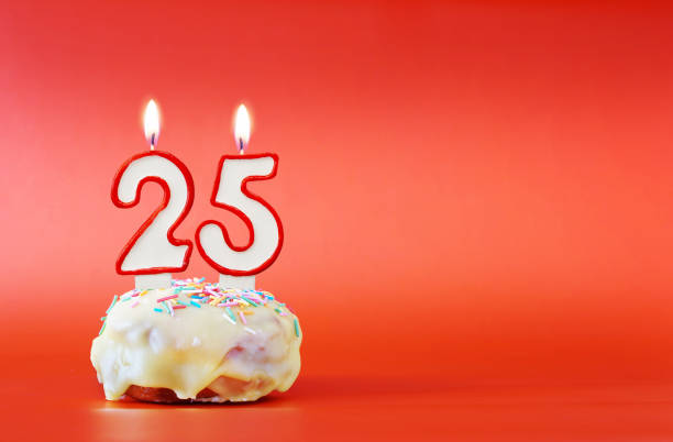 Twenty five years birthday. Cupcake with white burning candle in the form of number 25. Vivid red background with copy space Twenty five years birthday. Cupcake with white burning candle in the form of number 25. Vivid red background with copy space number 25 stock pictures, royalty-free photos & images