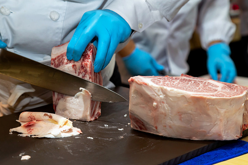 butchers or chefs are cutting and decorating highest  meat grade of marbling A5 japanese wagyu beef for barbecue menu and sell in japanese restaurant or butcher shop in japan.