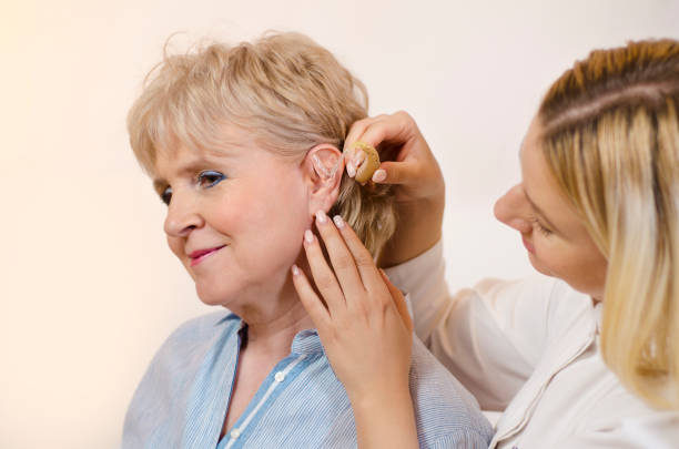 istock Nurse putting on hearing aid to woman 1138297720