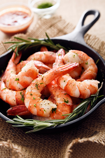 Tiger shrimps in a skillet cooking pan with cocktail sauce and seasoning