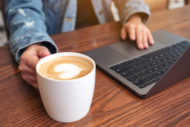 istock Closeup image of a woman using and touching on laptop touchpad on wooden table while drinking coffee 1138301231
