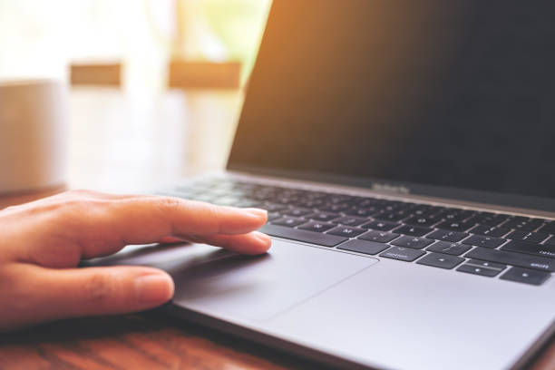 istock Closeup image of a hand using and touching on laptop touchpad with coffee cup on wooden table 1138301262