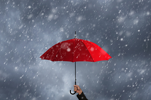 Red umbrella in the hands of businessmen amid a rainstorm.