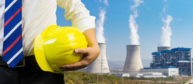 engineering management construction ,engineer or worker hold in hand yellow helmet for workers security  on working  site Coal power plant background.  business Man ,selective focus,vintage tone