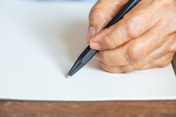 istock Senior woman's left Hand writing letter on ivory paper background, Notebook, A black pen, Close up & Macro shot, Selective focus, Stationery concept 1138314652