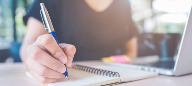 istock Woman hand is writing on a notepad with a pen.Web banner. 1138318104