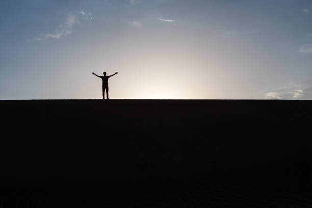 istock Raised hand silhouette on a dune in desert. 1138318116