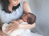 Close up portrait of beautiful young mother asian carrying little baby girl in home and sunlight in the morning. Healthcare, love, relationship concept