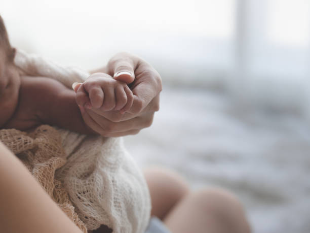 feche acima da terra arrendada da matriz entrega o bebê recém-nascido fêmea asiático e a luz solar na manhã. menina bonito três semanas velho. saúde, cuidado, amor, conceito de relacionamento. - newborn little girls baby lying down - fotografias e filmes do acervo