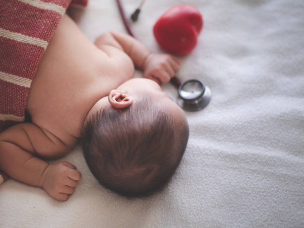 bebê recém-nascido fêmea asiático que dorme na cama com estetoscópio e luz solar na manhã. menina bonito três semanas velho. conceito da saúde do bebê - newborn little girls baby lying down - fotografias e filmes do acervo