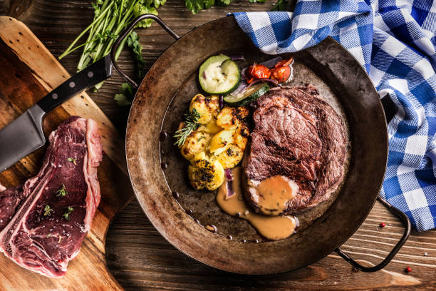 jugosa carne de ternera rib eye asado con salsa de pimienta salada de verduras y hierbas en la sartén vintage - round of beef fotografías e imágenes de stock