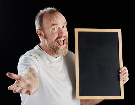 Friendly mature man shows blank chalkboard for your message