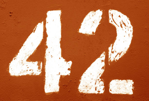 istock Number 42 in stencil on rusty metal wall in orange tone. 1138334057