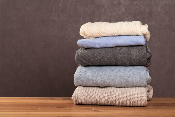 istock Bunch of knitted warm pastel color sweaters with different knitting patterns folded in stack on brown wooden table, grunged texture wall background 1138334582